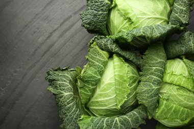 Fresh Savoy cabbages on black textured table, flat lay. Space for text