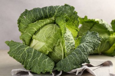 Fresh Savoy cabbages on light grey table, closeup