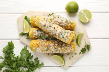 Lezzetli ızgara mısır koçanları maydanozlu, peynirli ve limon dilimli beyaz ahşap masa, düz uzanmış