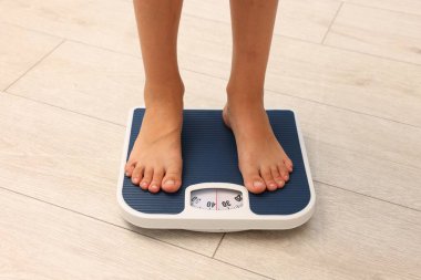 Küçük çocuk terazinin içinde duruyor, yakın plan.