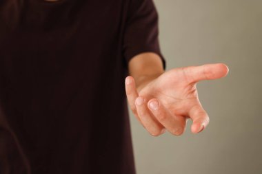 Açık gri arka planda bir şey tutan adam, yakın plan.