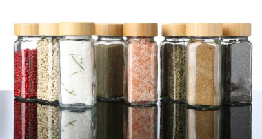 Ayna yüzeyindeki kavanozlardaki farklı baharatlar beyaz arkaplana karşı