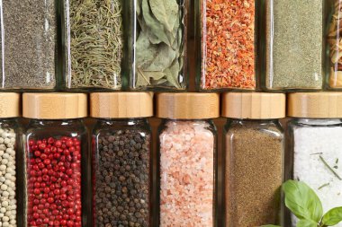 Different spices and jars on wooden background, closeup