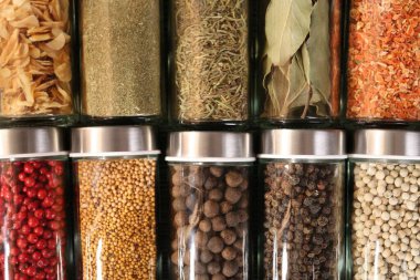 Different spices in glass jars as background, top view