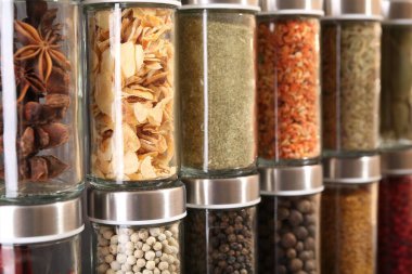 Arka plan olarak cam kavanozlardaki farklı baharatlar, yakın plan