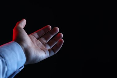 Siyah arka planda bir şey tutan adam, yakın plan. Metin için boşluk