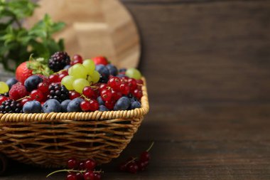 Hasır sepetin içinde farklı olgun böğürtlenler, ahşap masada, yakın plan. Metin için boşluk