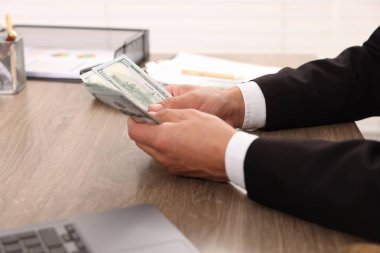 Ahşap masada dolar sayan adam, yakın plan.