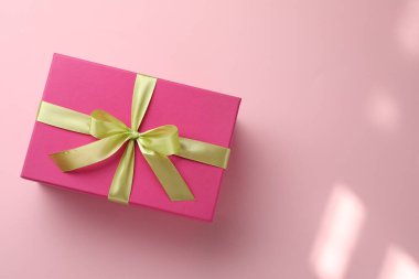 Pembe arka planda fiyonklu güzel bir hediye kutusu, üst manzara. Metin için boşluk