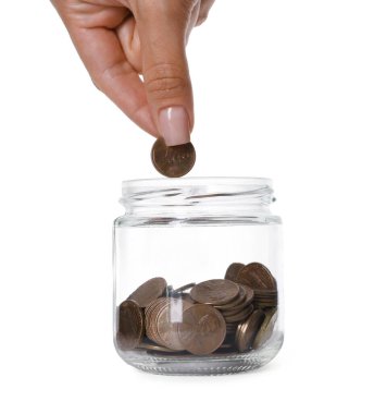 Kadın beyaz arka planda cam kavanoza para koyuyor.