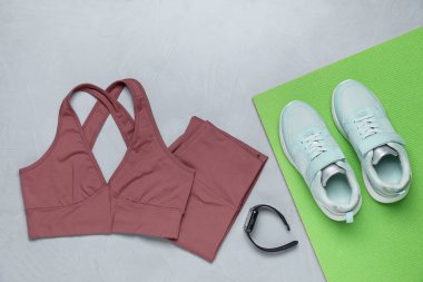 Spor kıyafetleri, ayakkabılar ve saat gri arka plan, düz yatış