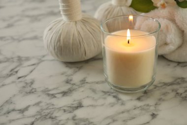 Beautiful spa composition with burning candle on white marble table, closeup. Space for text