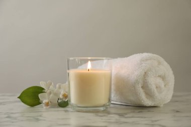 Beautiful spa composition with burning candle on white marble table, closeup