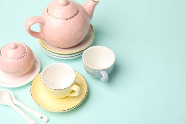Beautiful ceramic tea set for children on turquoise background. Space for text