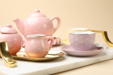 Tray with beautiful ceramic tea set for children on beige background, closeup