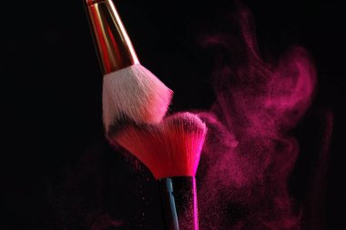 Siyah arka planda pembe göz farlı makyaj fırçaları, yakın plan