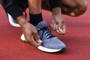 Stadyumda ayakkabısının bağcıklarını bağlayan koşucu, yakın plan.