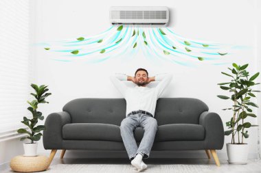 Klimalı kanepede dinlenen mutlu adam.