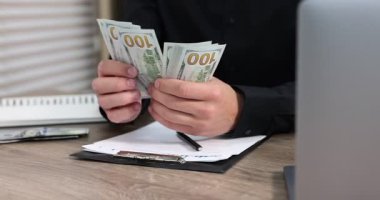 Ahşap masada dolar sayan adam, yakın plan.