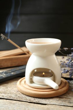 Aroma lambası yanan mum ve yanan tütsü ile ahşap masa üzerinde koyu arkaplan, yakın çekim