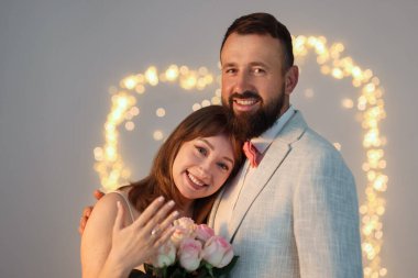 Evlilik teklifi yapıyor. Nişan yüzüklü bir kadın ve açık gri arka planda mutlu nişanlısı, bulanık ışıklar, bokeh etkisi.