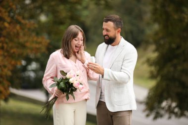 Nişan yüzüklü bir adam kız arkadaşına dışarıda evlenme teklif ediyor.