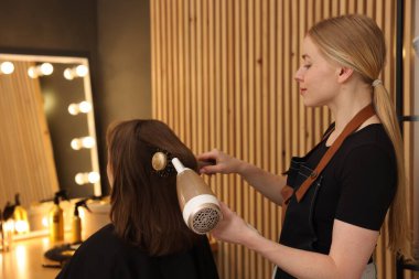 Kuaför kuaförde müşterinin saçını kurutuyor.