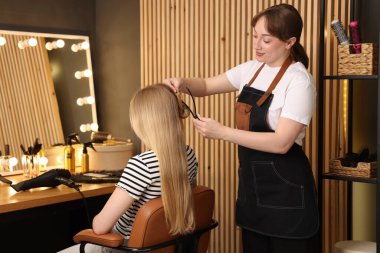 Profesyonel kuaför müşteriyle kuaförde çalışıyor.