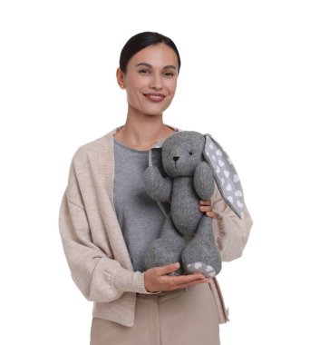 Beyaz arka planda oyuncak tavşanla gülümseyen çocuk odası öğretmeni.