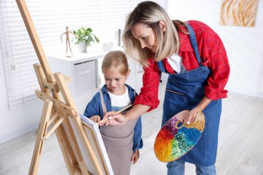 Meslek seçimi. Anne kızına stüdyoda resim yapmayı öğretiyor.