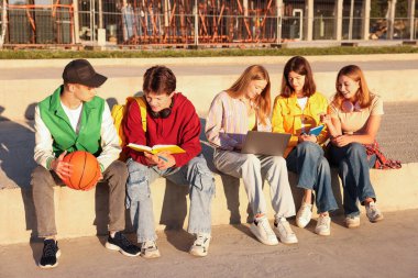 Dışarıda ödev yapan bir grup genç.