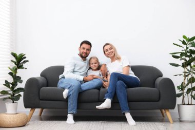 Mutlu aile evdeki kanepede birlikte vakit geçiriyor.