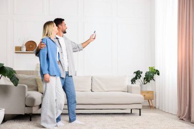 Evdeki klimayı uzaktan kumandayla kontrol eden çift. Metin için boşluk