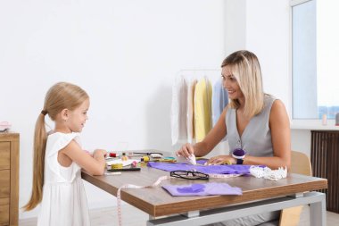 Meslek seçimi. Küçük kız atölyede çalışan annesine yardım ediyor.