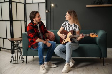 Evdeki kanepede gitar çalmayı öğreten öğretmen.