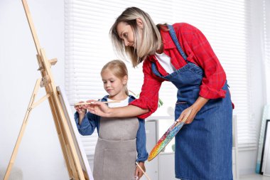 Meslek seçimi. Anne kızına stüdyoda resim yapmayı öğretiyor.