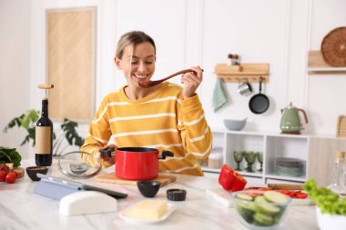 Mutfaktaki masada yemek yapan gülümseyen kadın.
