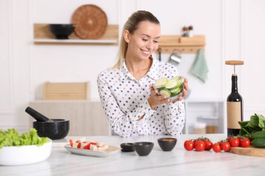 Mutfaktaki masada kabak dilimleri ile gülümseyen kadın.