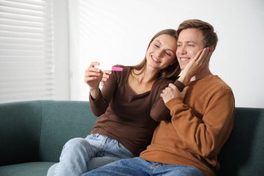 Evdeki koltukta hamilelik testi olan mutlu çift.