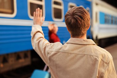 Hoşçakalın. Trenin yanında sevgilisine el sallayan bir adam, seçici bir odak noktası.