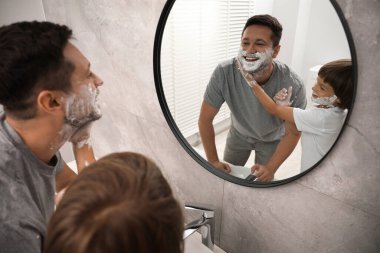 Banyoda yüzlerinde tıraş köpüğü olan baba ve oğul.