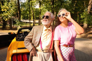 Modern Cabriolet yakınlarında güneş gözlüklü şık bir çift.