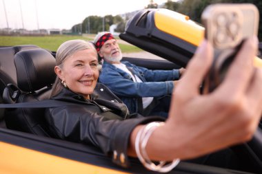 Üst düzey kadın özçekim yaparken erkek açık havada Cabriolet kullanıyor, seçici odaklanma.