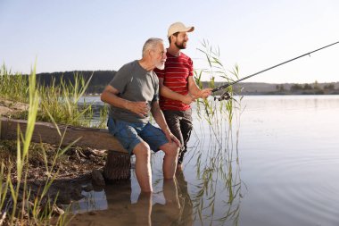 Yaşlı babası ve mutlu oğlu nehirde birlikte balık tutuyorlar.
