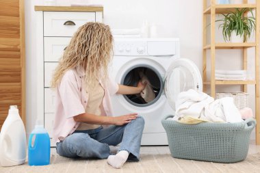 Kirli çamaşırları çamaşır makinesine koyan kadın.