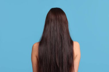 Açık mavi arka planda saçı zarar görmüş bir kadın.