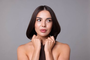 Açık gri arkaplandaki laminasyon prosedüründen sonra güzel pürüzsüz saçlı kadın