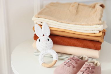 Temiz bebek kıyafetleri ve aksesuarlar beyaz masa içinde, yakın plan.