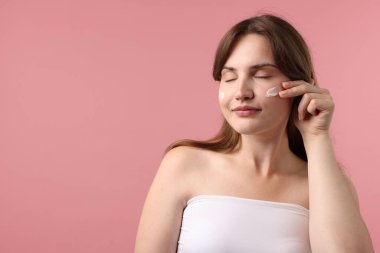 Yüzünde pembe arka planda krem olan güzel bir kadın. Metin için boşluk