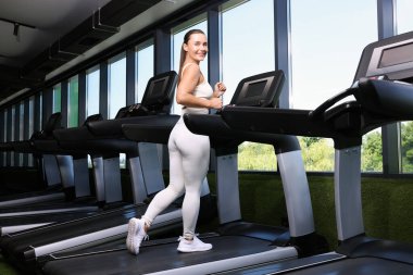 Koşu bandında gülümseyen kadın antrenmanı, düşük açı.